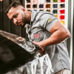 Man expertly applying car wrap in a modern automotive workshop.