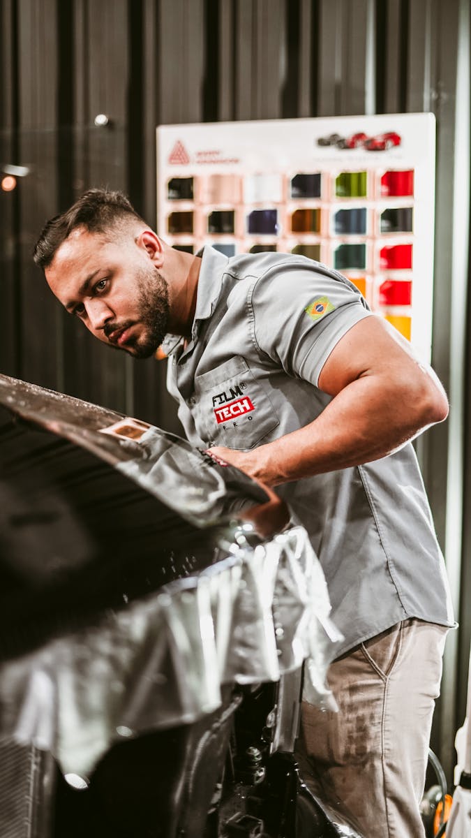 Man expertly applying car wrap in a modern automotive workshop.