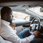 man in white dress shirt driving car during daytime